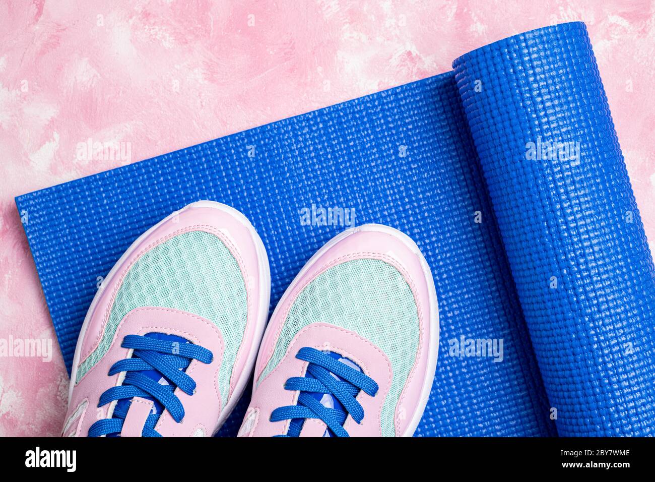 Sport et mode de vie sain. Tapis de yoga et chaussures de sport sur fond rose. Équipement de sport. Vêtements de sport féminins et tendance pour le fitness et le yoga Banque D'Images