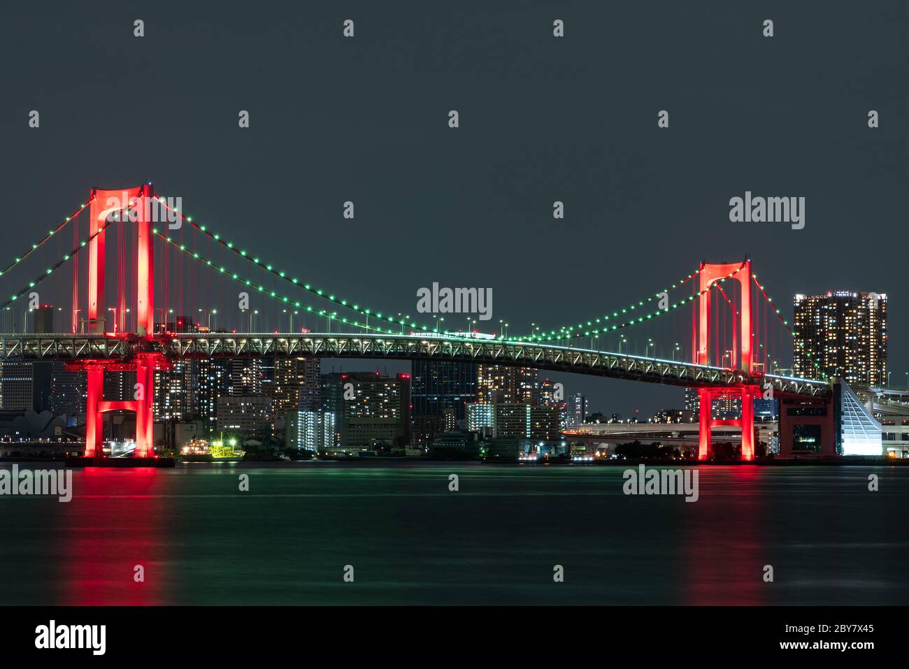 Vue nocturne du pont Rainbow, illuminé en rouge comme un signe de 'Tokyo Alert (alerte de coronavirus pour la région de Tokyo)' à Odaiba, Japon. Banque D'Images