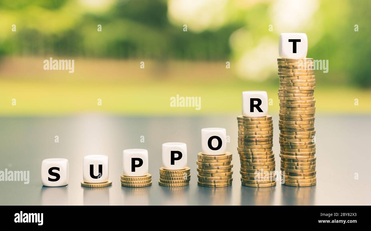 Symbole de soutien financier en raison de la crise de corona, Dice forme le mot 'support' sur les piles de plus en plus grandes de pièces. Banque D'Images