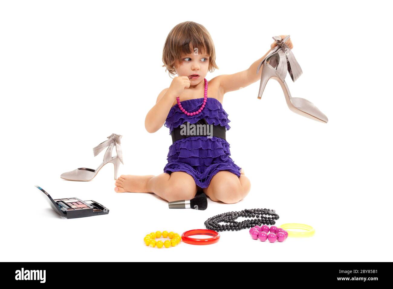 Petite fille mignonne avec des cosmétiques et des chaussures pour femmes dans le studio Banque D'Images