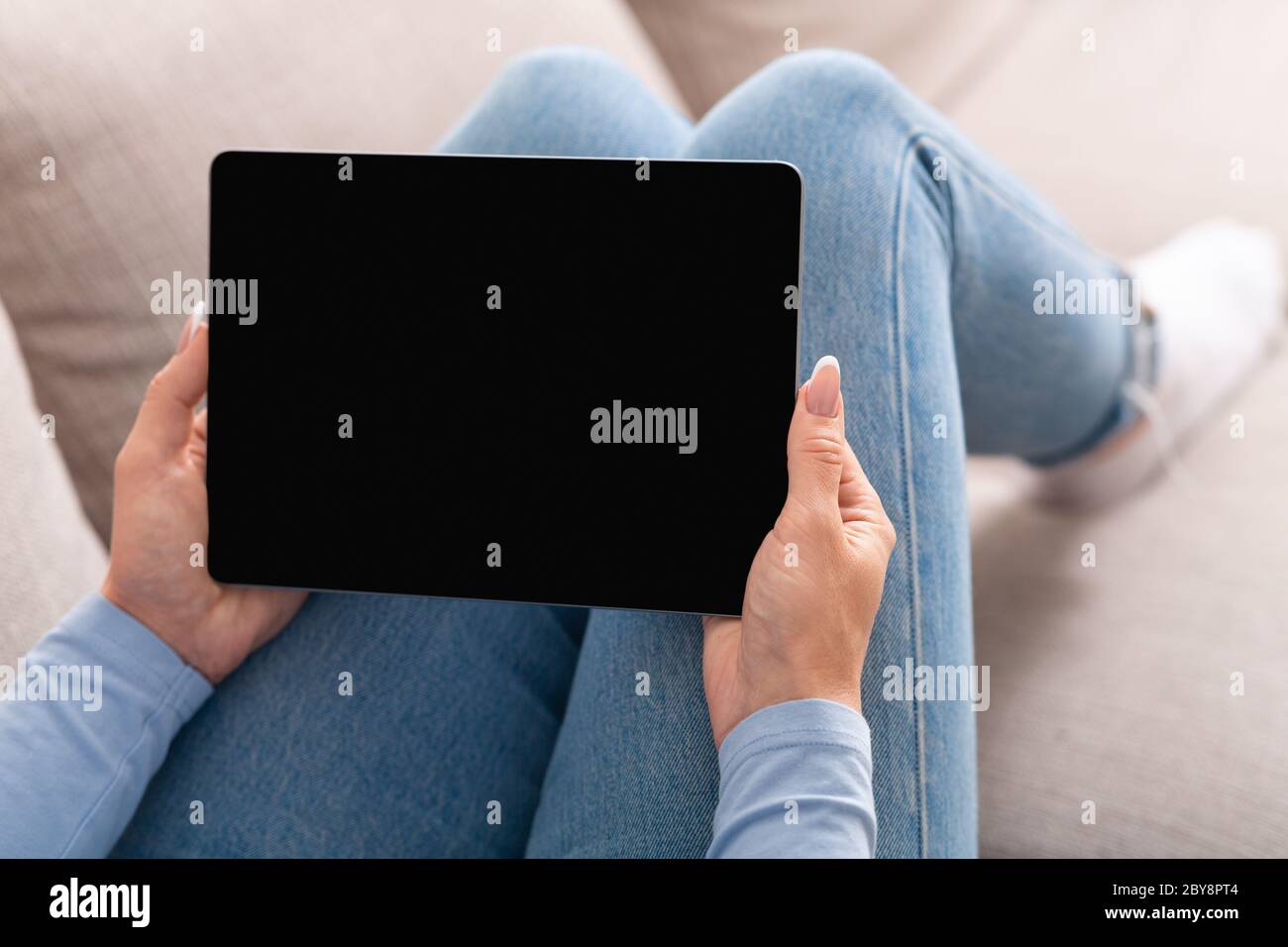 Appels vidéo et technologie intelligente. Une femme tient la tablette dans les mains, assis sur le canapé Banque D'Images