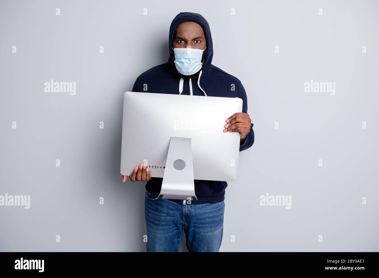 Photo de la peau sombre voleur africain porter TV moniteur volé fou mal personne n'ont pas d'argent crise de quarantaine forcé cambriolage masque facial capuche sur la tête Banque D'Images