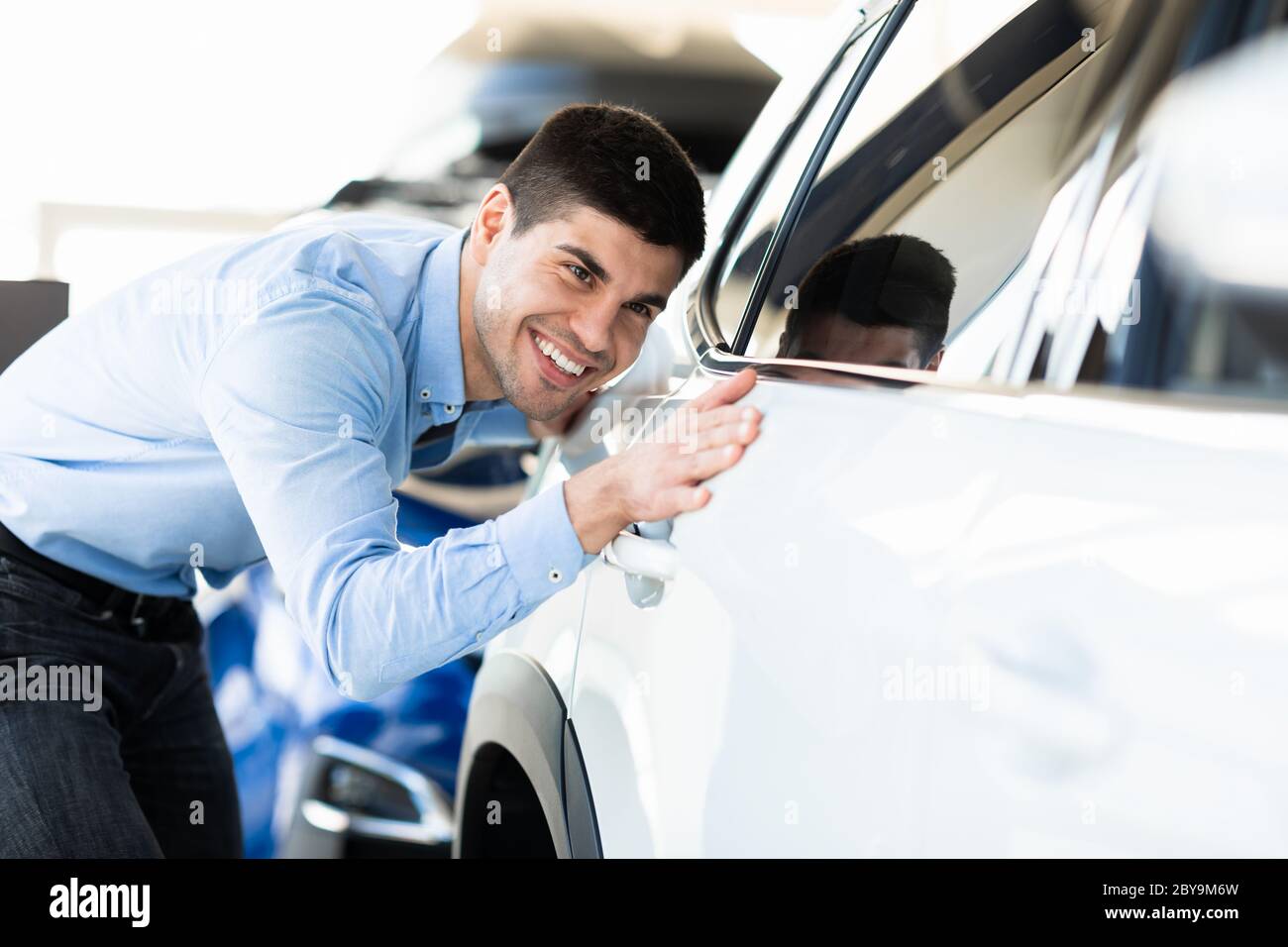 Homme touchant sa nouvelle voiture dans la salle d'exposition de la concession Banque D'Images