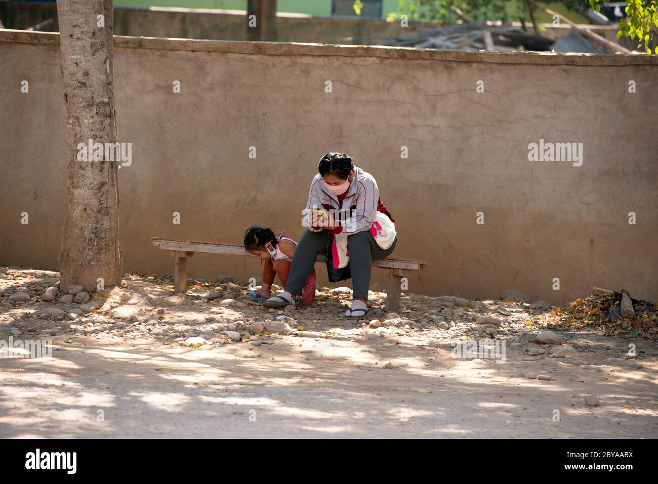 Une mère et sa fille se réfugient au soleil en attendant un bus dans la petite ville de Luang Namtha, au nord du Laos. Banque D'Images