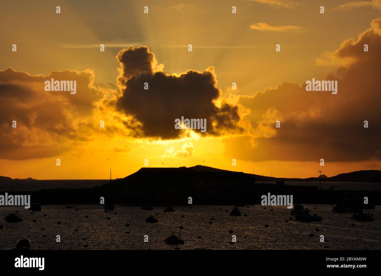 Le soleil se couche derrière un nuage au-dessus du port de St Marys sur les îles de Scilly.Cornwall Royaume-Uni Banque D'Images