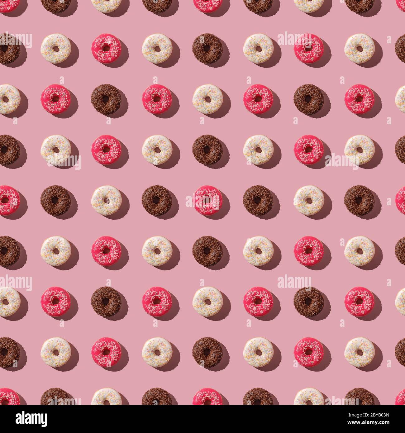 Beignets roses, vanille et chocolat avec saupoudrer, motif sans couture, dessert glacé sucré sur fond rose minimal, vue du dessus Banque D'Images