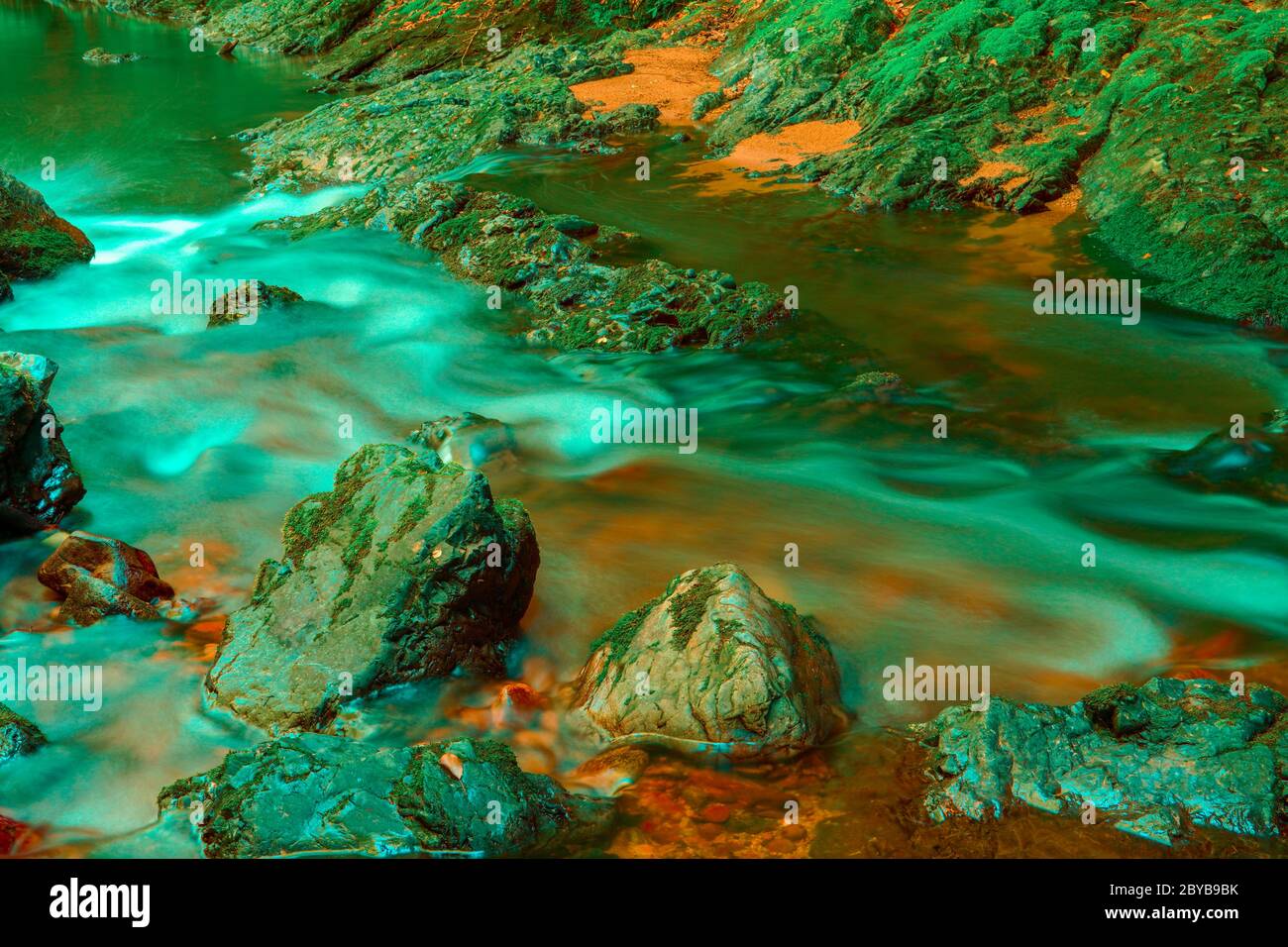 Pierres dans un ruisseau avec de l'eau brouillée par une longue exposition Banque D'Images