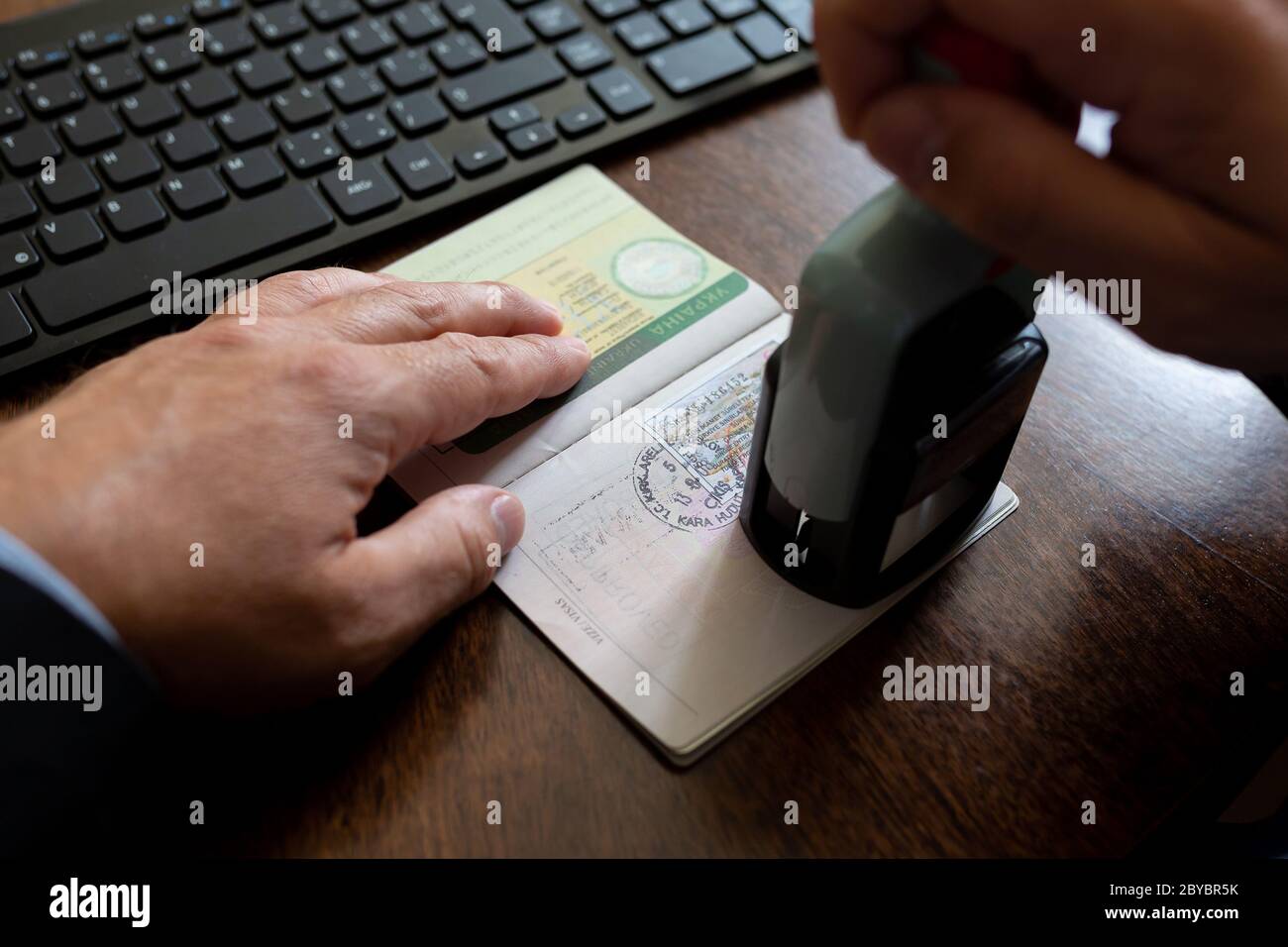 L'agent de contrôle de l'immigration doit apposer le cachet d'arrivée sur le passeport Banque D'Images