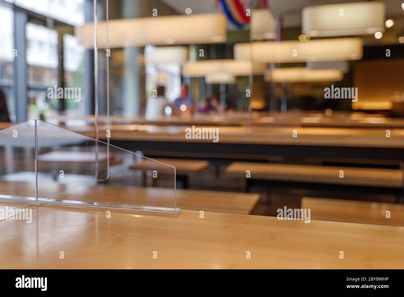 Cloison acrylique transparente temporaire sur table en bois pour faire social distancer dans la réouverture Restaurant pendant l'épidémie de COVID-19 avec la Nouvelle normale Banque D'Images