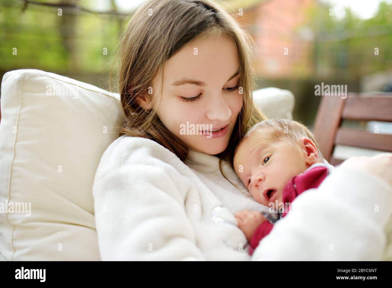 Jolie grande sœur admirant son frère nouveau-né. Adorable jeune fille qui tient son nouveau frère de garçon. Enfants avec un grand écart d'âge. Grande différence d'âge entre les deux Banque D'Images