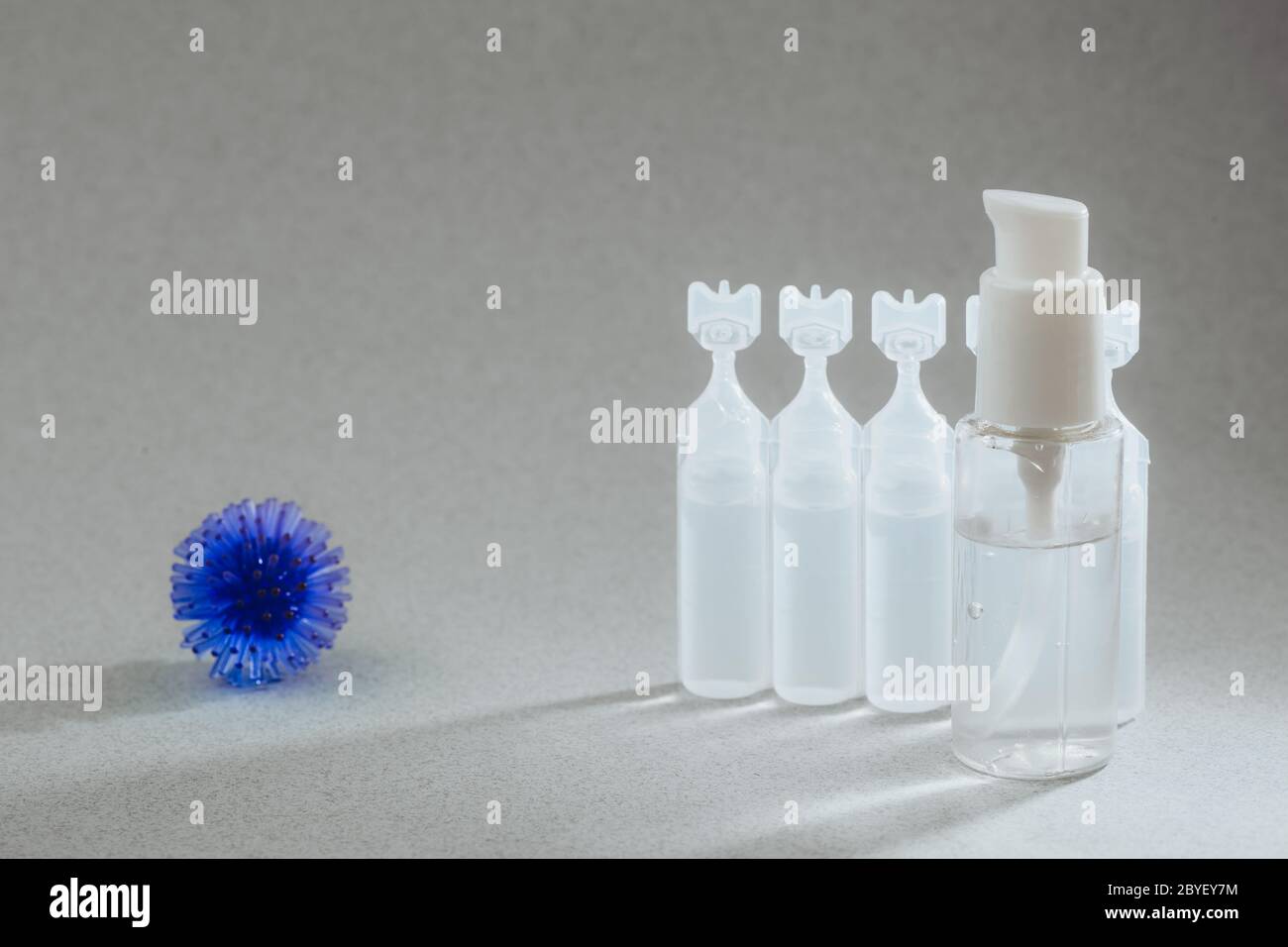 Modèle abstrait du coronavirus, ampoule avec médicament et flacon avec gel antibactérien pour les mains sur fond gris. Concept d'hygiène pour combattre le virus. Banque D'Images