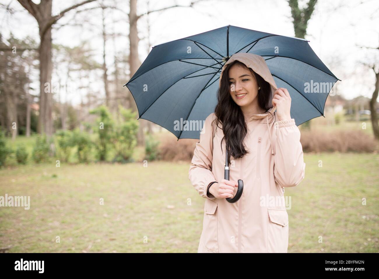 Style de vie, concept de voyage.modèle sous la pluie. Femme d'été dans le parc lors d'une randonnée pluvieuse et sombre dans le parc et porte un parapluie Banque D'Images