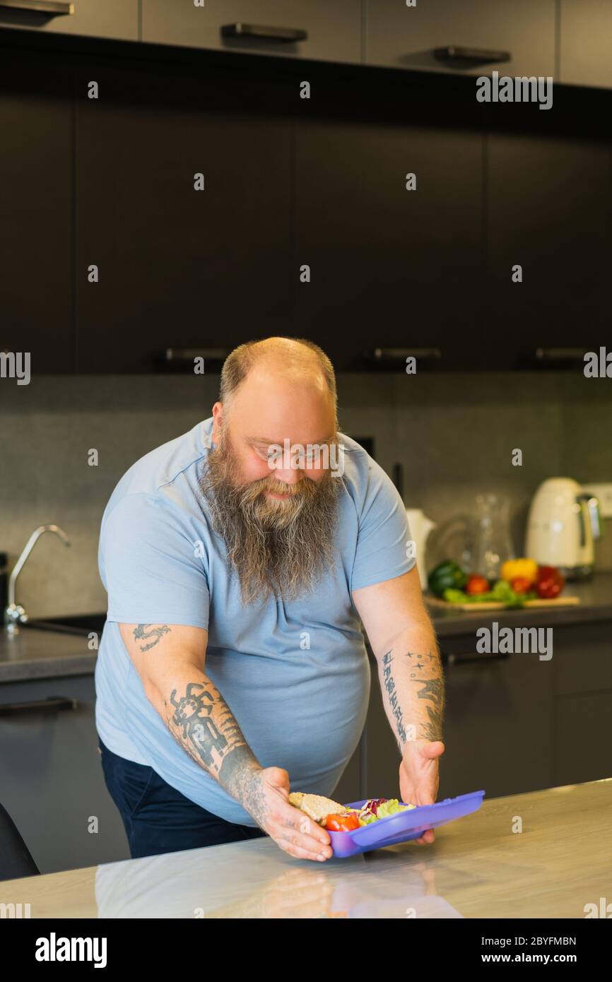 Se réjouir chauve gros homme ouvrant sa boîte à lunch Banque D'Images