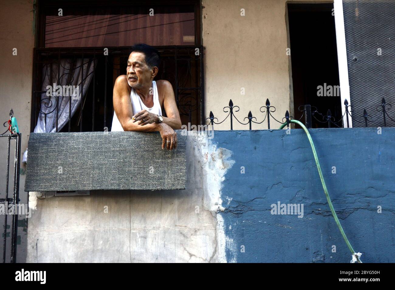 Antipolo City, Philippines - 5 juin 2020 : l'homme philippin adulte se repose sur le porche de son appartement. Banque D'Images