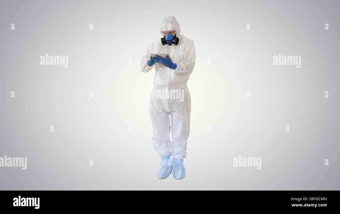 Médecin de sexe masculin en costume de protection utilisant une tablette numérique sur fond dégradé. Banque D'Images