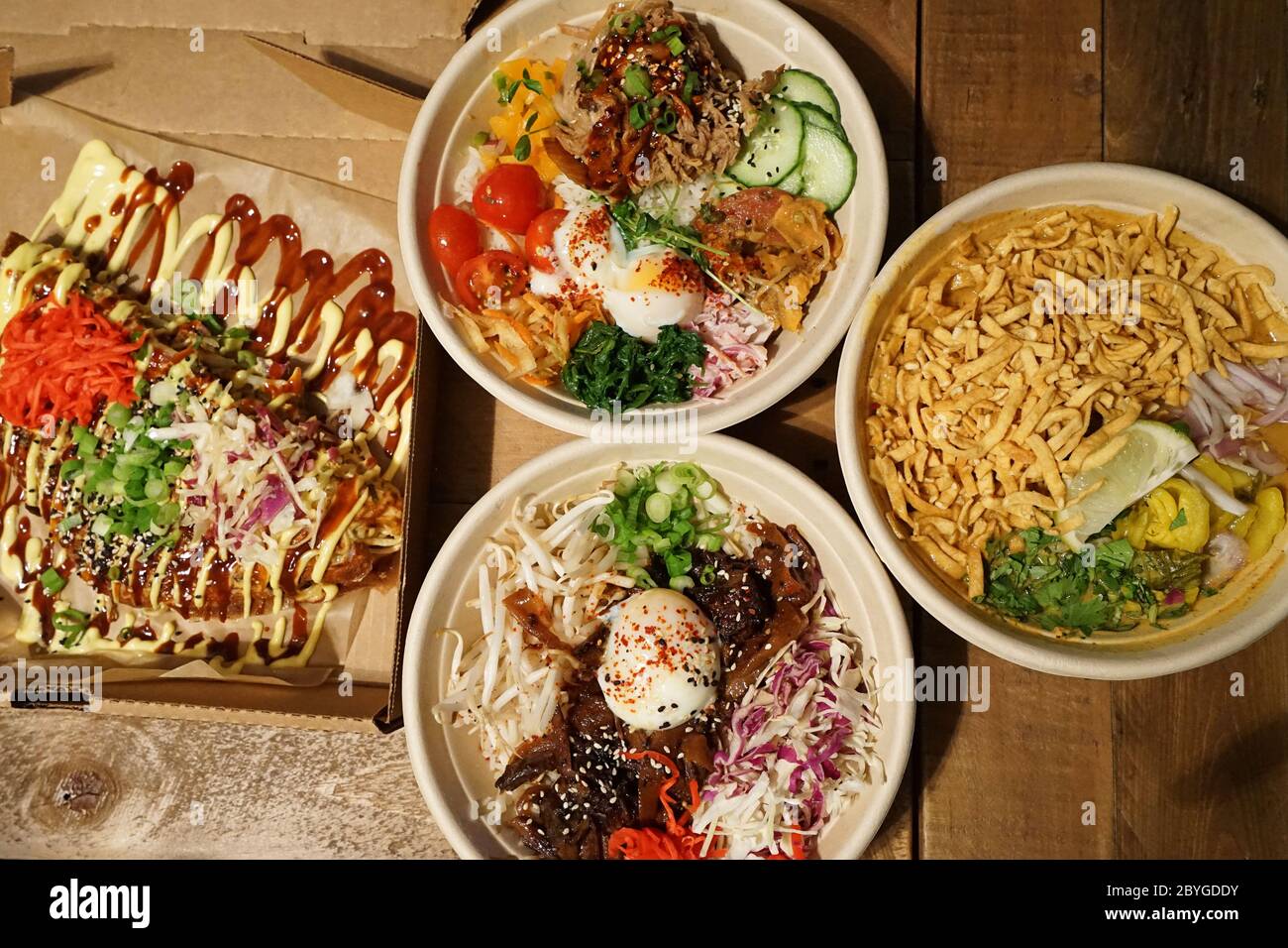 Bœuf et poulet sur le riz dans le style coréen servi avec Okonomiyaki (crêpes japonaises) et Khao soi, soupe de nouilles au curry du nord de la Thaïlande Banque D'Images