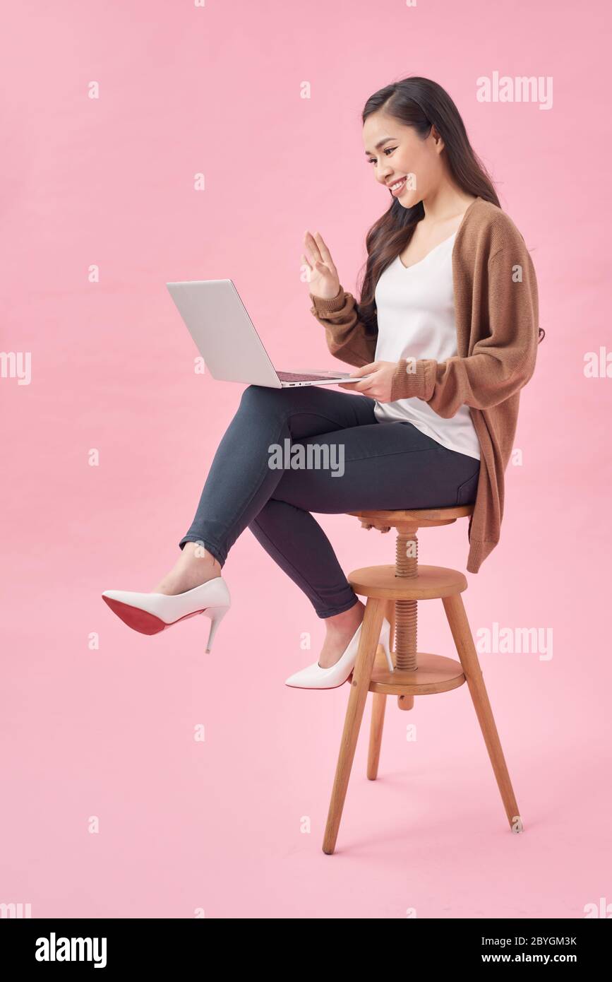Femme joyeuse assise sur une chaise et utilisant un ordinateur portable Banque D'Images