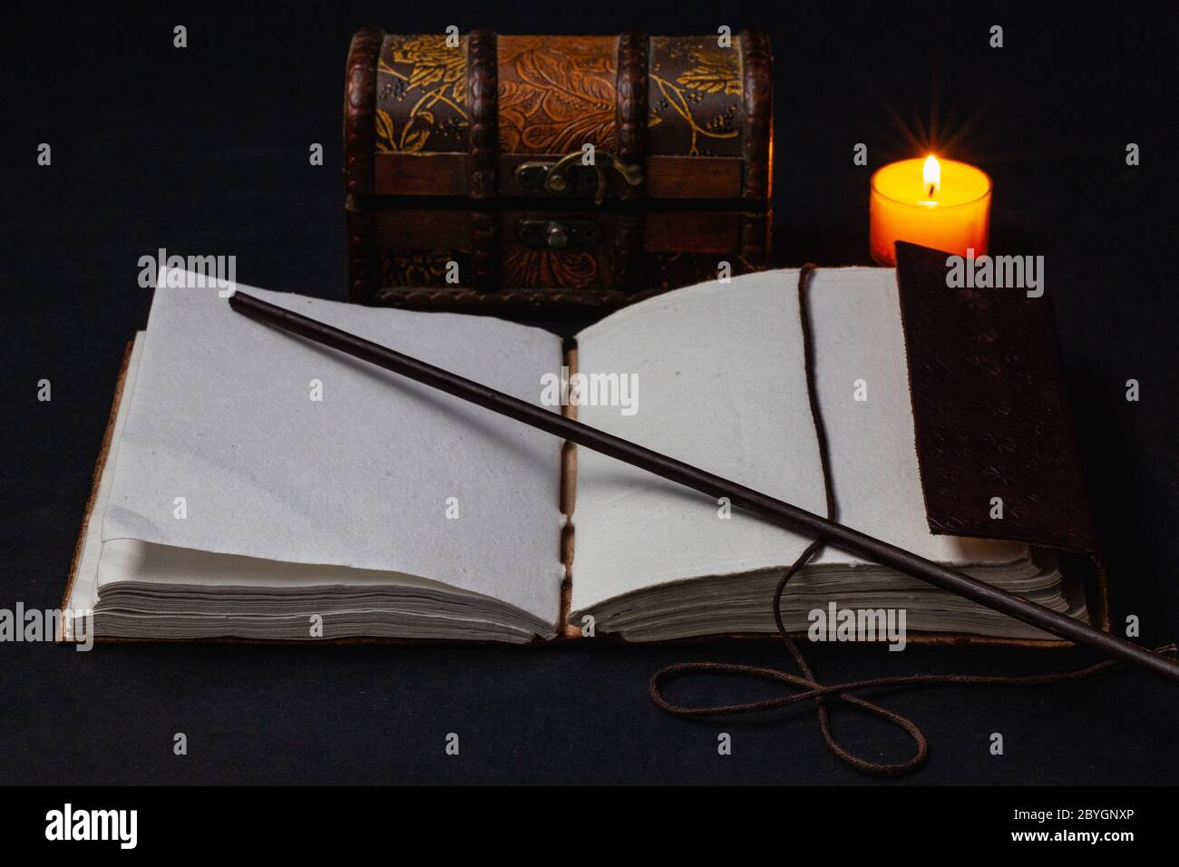 Image d'un livre magique ouvert et d'une baguette sur la table dans la pièce sombre. Banque D'Images