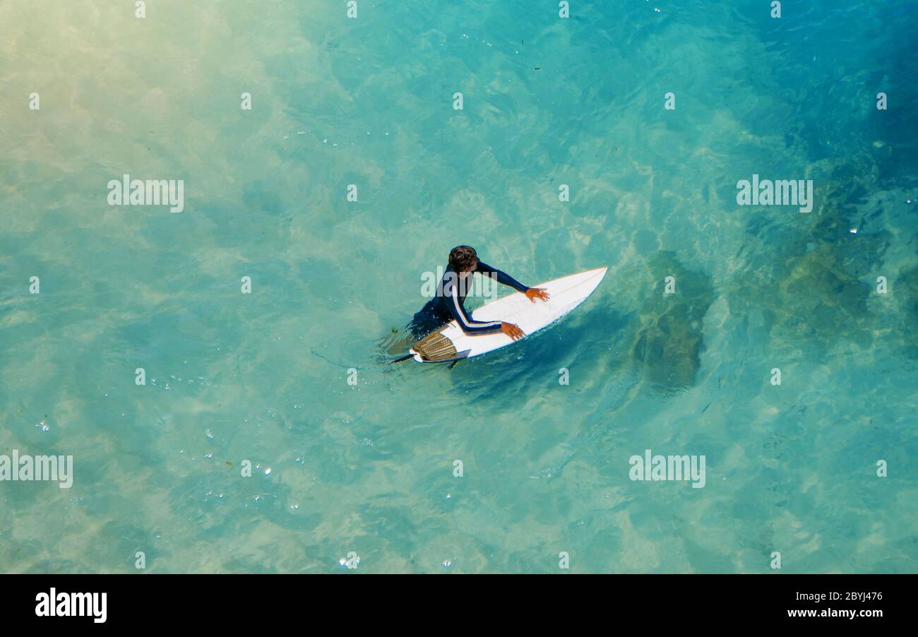 Jeune surfeur sportif qui porte sa planche à surf et qui va à la vue sur l'océan. Riche belle couleur eau comme un fond pour le blog de voyage ou site Web. Banque D'Images