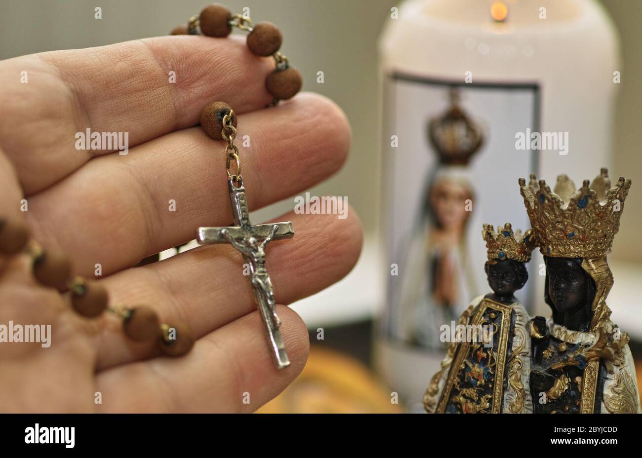 Main humaine tient rosario. Sculpture et bougie de Saint Mary. Équipement catholique prier. Banque D'Images