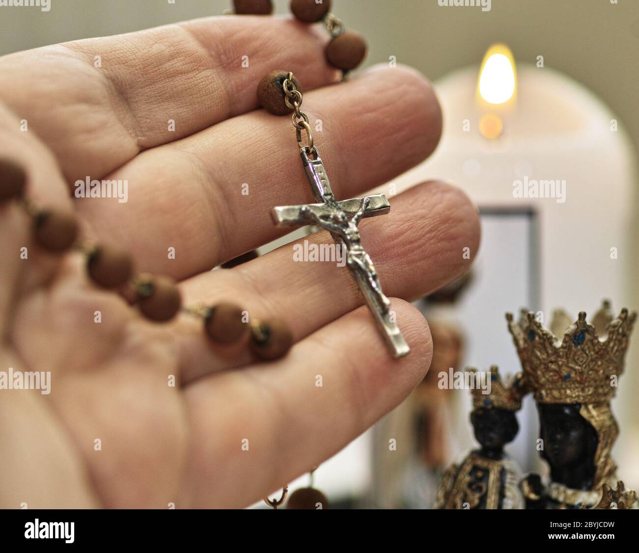 Main humaine tient rosario. Sculpture et bougie de Saint Mary. Équipement catholique prier. Banque D'Images