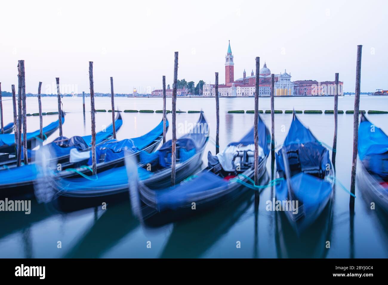 Paysage paisible avec ciel clair de lever de soleil sur la piazza San Marco à Venise. Rangée de gondoles garées sur le quai de la ville. Eglise de San Giorgio Maggiore en arrière-plan, Italie, Europe Banque D'Images