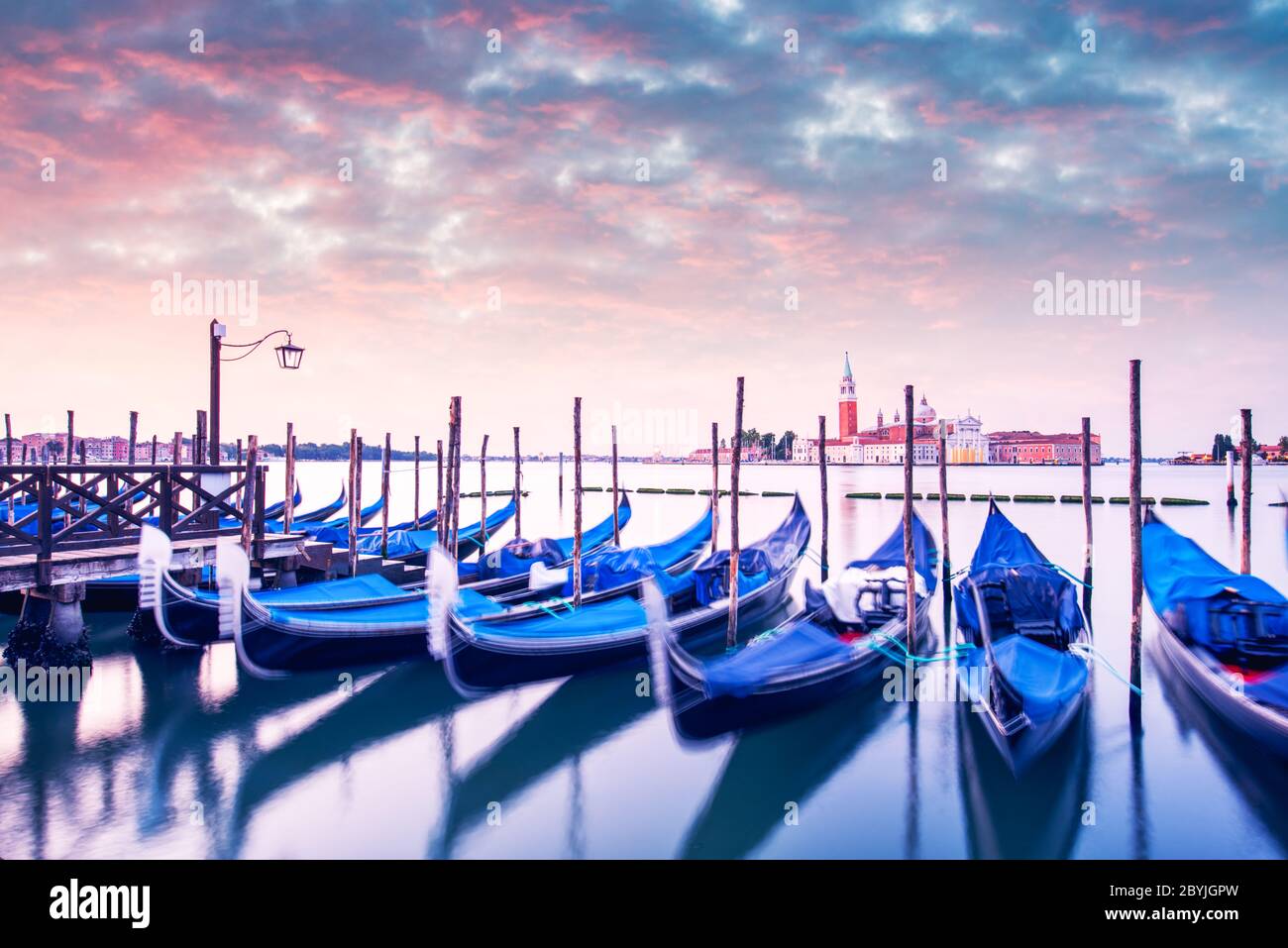 Paysage coloré avec ciel rose au coucher du soleil sur la piazza San Marco à Venise. Rangée de gondoles garées sur le quai de la ville. Eglise de San Giorgio Maggiore en arrière-plan, Italie, Europe Banque D'Images