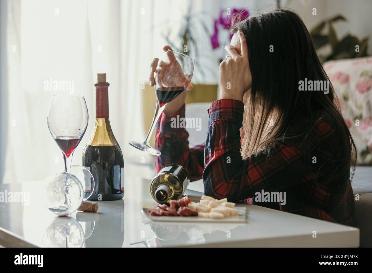 Triste femme fatiguée, boire du vin à la maison, seule, assise sur le sol dans le salon, se sentant déprimé Banque D'Images