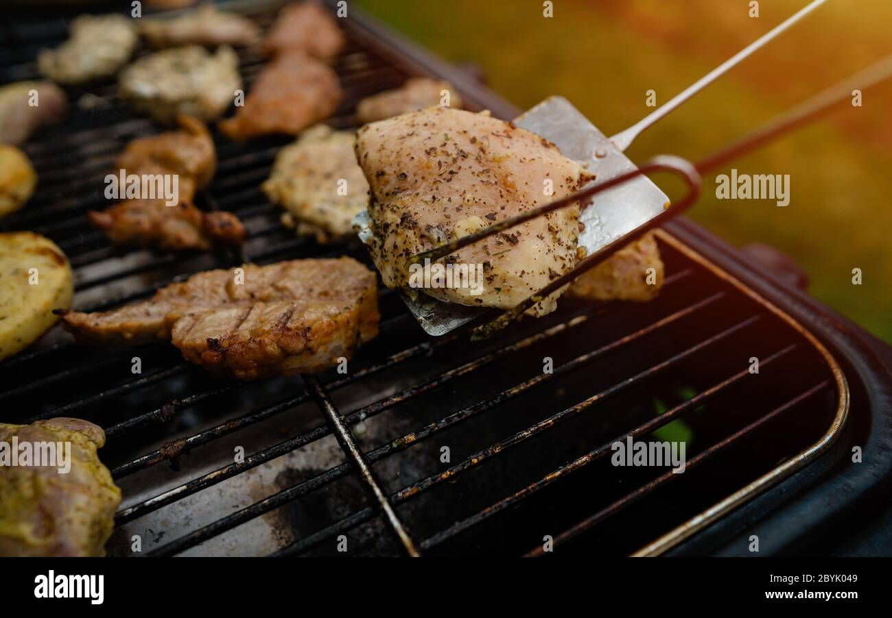 Viande grillée au barbecue avec flammes et plats de viande dans l'après-midi du week-end. Gros plan sur la viande grillée fraîche en préparation sur le gril. Banque D'Images
