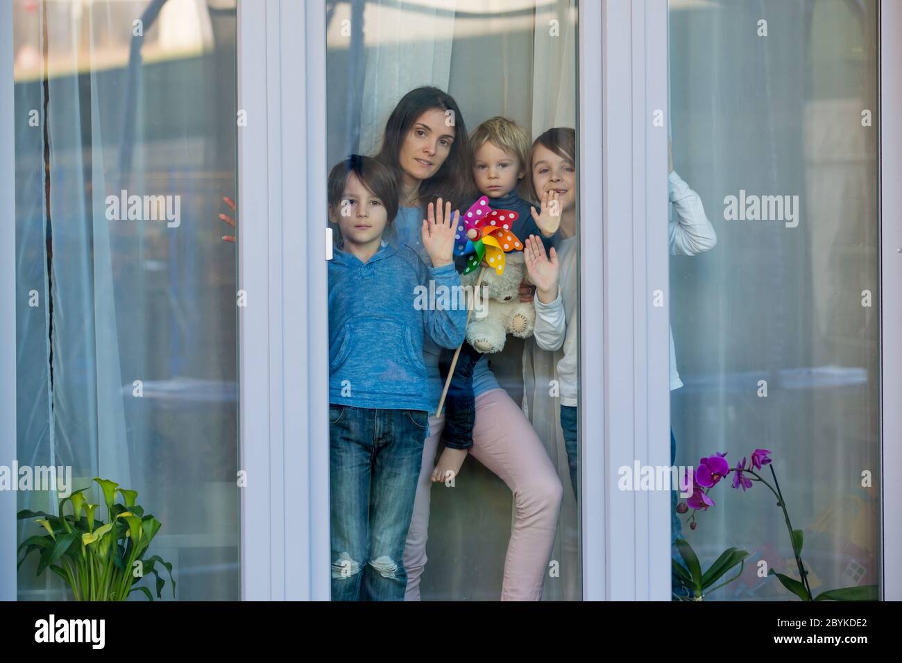 Famille, debout derrière la fenêtre, à la maison, quarantaine due au coronavirus Banque D'Images