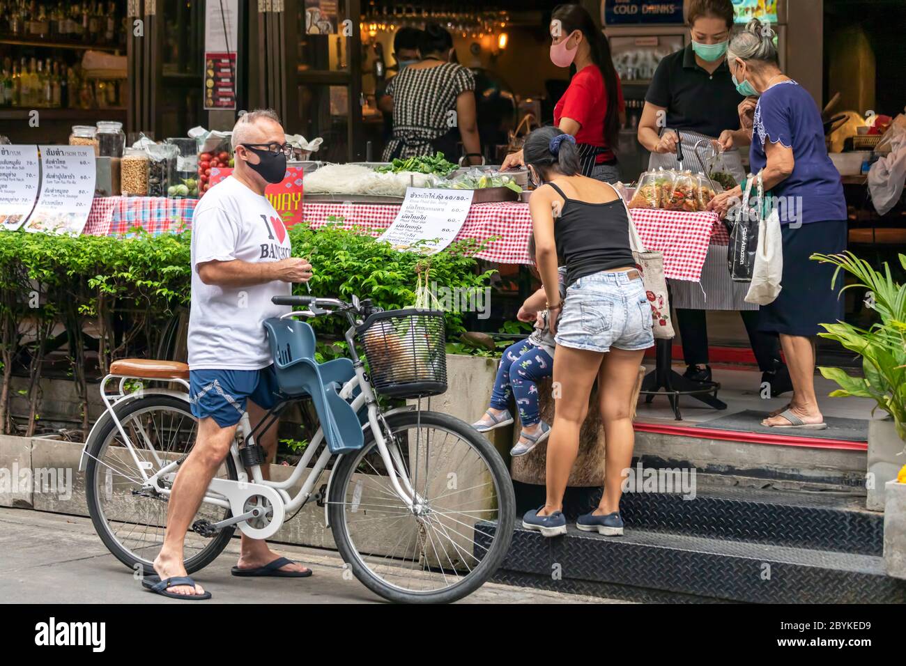 Famille avec masque facial et vélo à emporter au stand de nourriture pendant la pandémie de Covid, Bangkok, Thaïlande Banque D'Images
