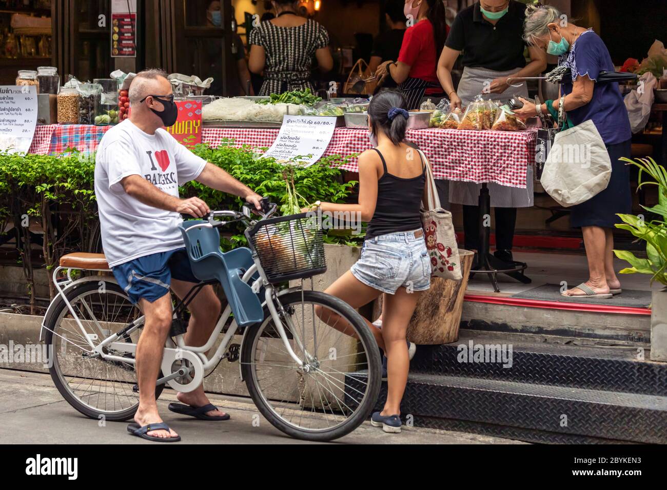 Famille avec masque facial et vélo à emporter au stand de nourriture pendant la pandémie de Covid, Bangkok, Thaïlande Banque D'Images