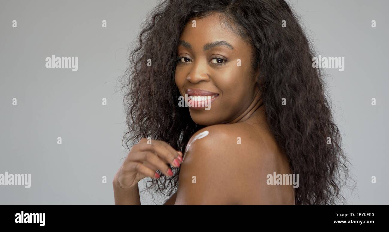 Une dame noire se maquant de la crème sur l'épaule Banque D'Images