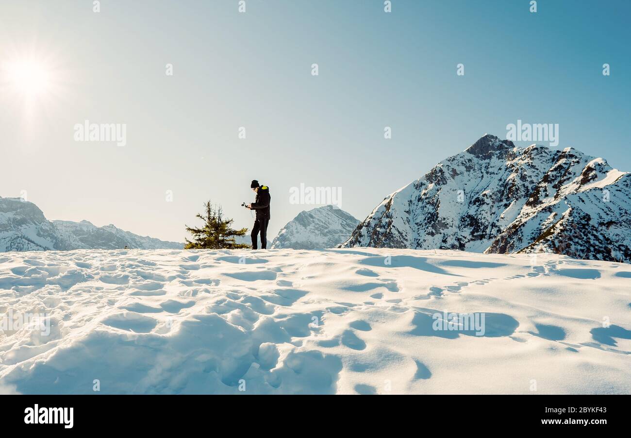 Photographe homme prenant des photos sur le pic de montagne du coucher du soleil. Montagne pendant un coucher de soleil d'hiver vibrant. Alpinisme extrême en hiver. Belles Alpes hiver l Banque D'Images