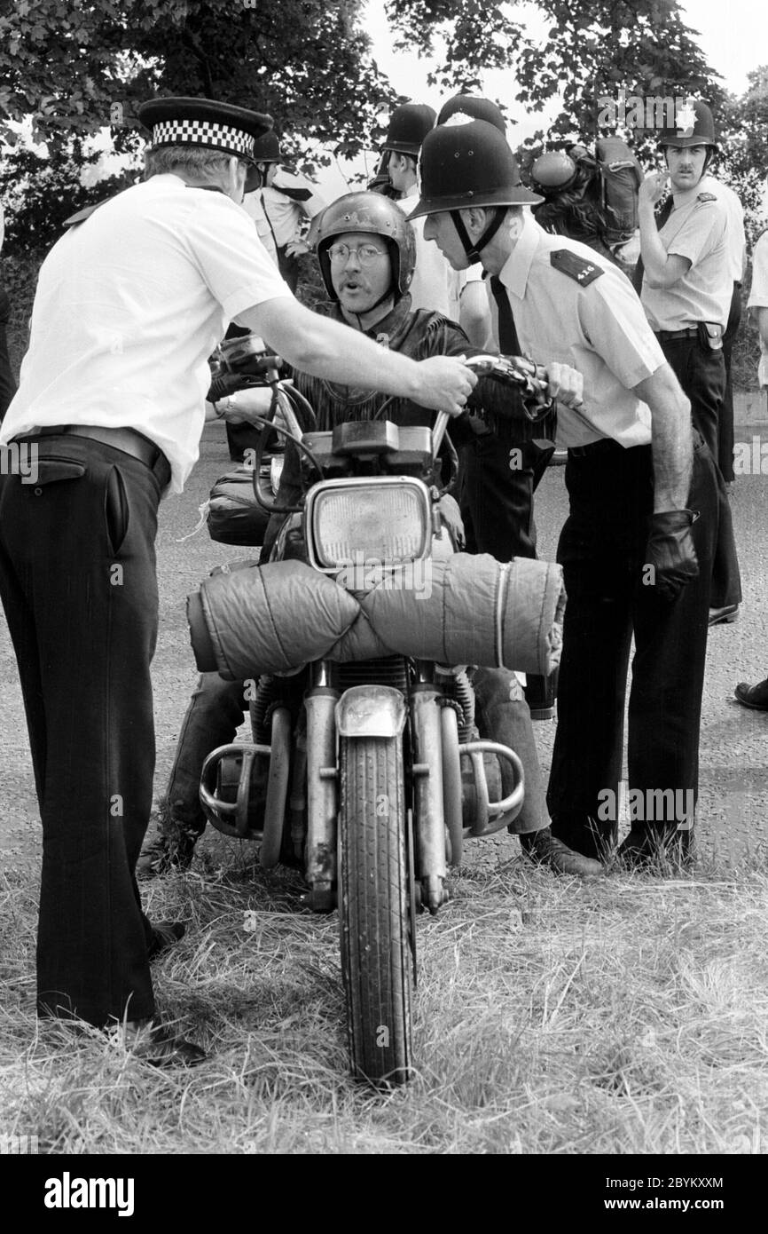 La police arrête un voyageur du nouvel âge sur une moto près de Stonehenge avant le solstice d'été 1985. Wiltshire Royaume-Uni. Banque D'Images