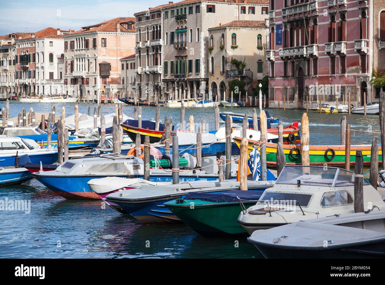 Des lancements de véhicules et des bateaux ouverts amarrés le long du Grand Canal à Venise, en Italie, avec des bâtiments au bord du canal en arrière-plan Banque D'Images