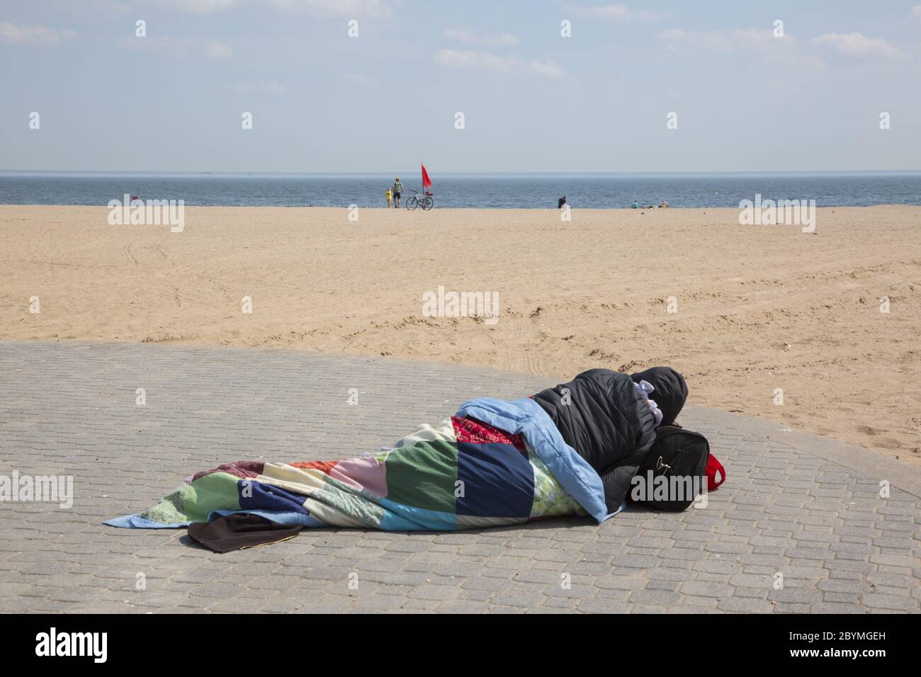 Un homme sans abri dort sur une plage vide de Coney Island en raison de la pandémie de Covid-19. Brooklyn, New York. Banque D'Images
