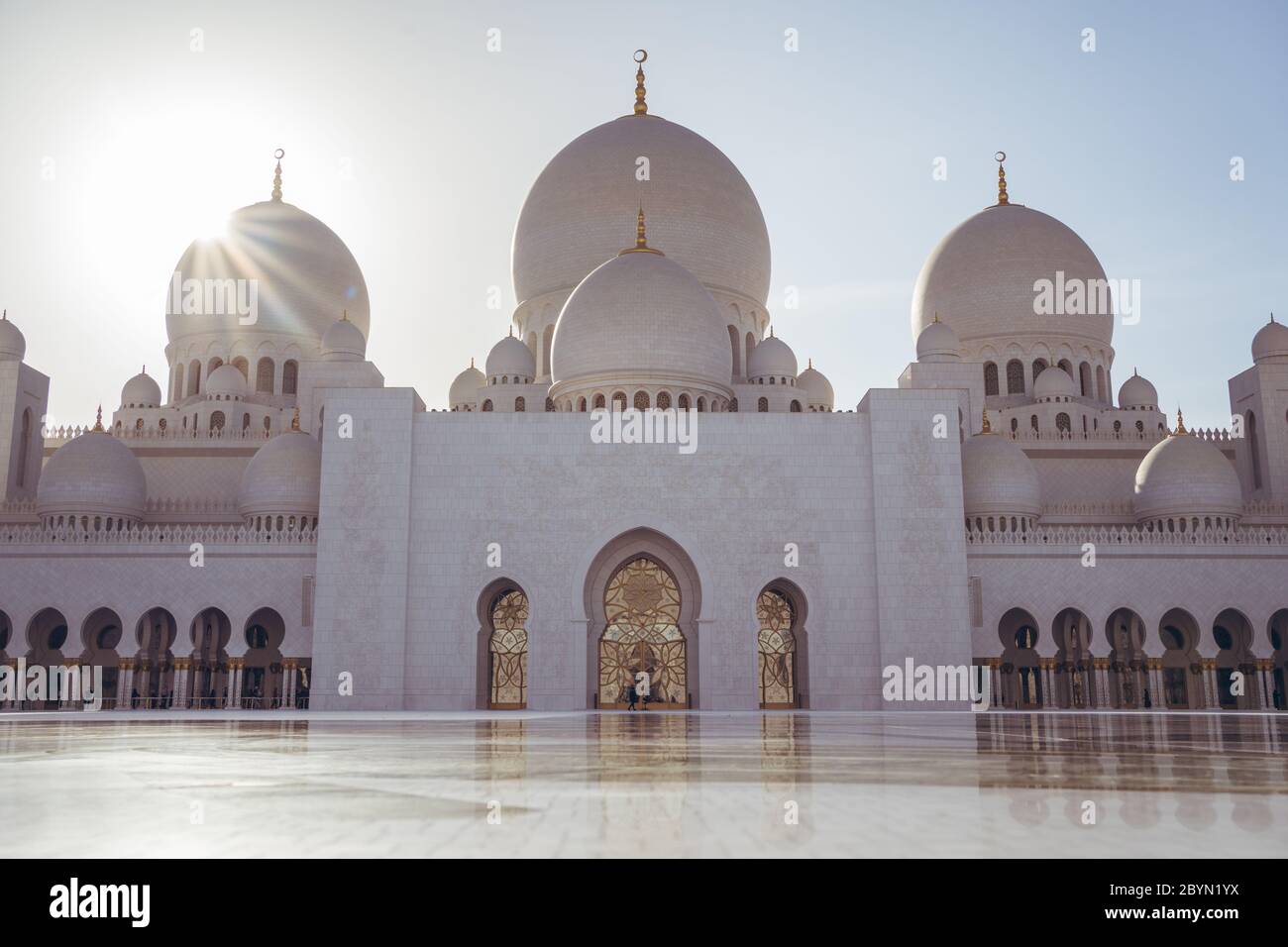 Abu Dhabi / Émirats arabes Unis - 5 février 2020 : étoile du soleil derrière le dôme de la Grande Mosquée Sheikh Zayed au coucher du soleil Banque D'Images