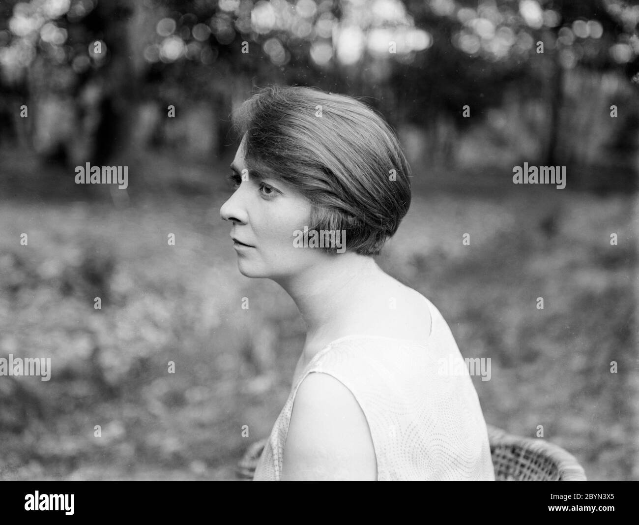Une photographie de portrait anglais vintage des années 1920 en noir et blanc, montrant une vue latérale de la tête de jeune femme peut attirer. La photo est prise à l'extérieur avec la lumière naturelle, et montre la coiffure des années 1920. Banque D'Images
