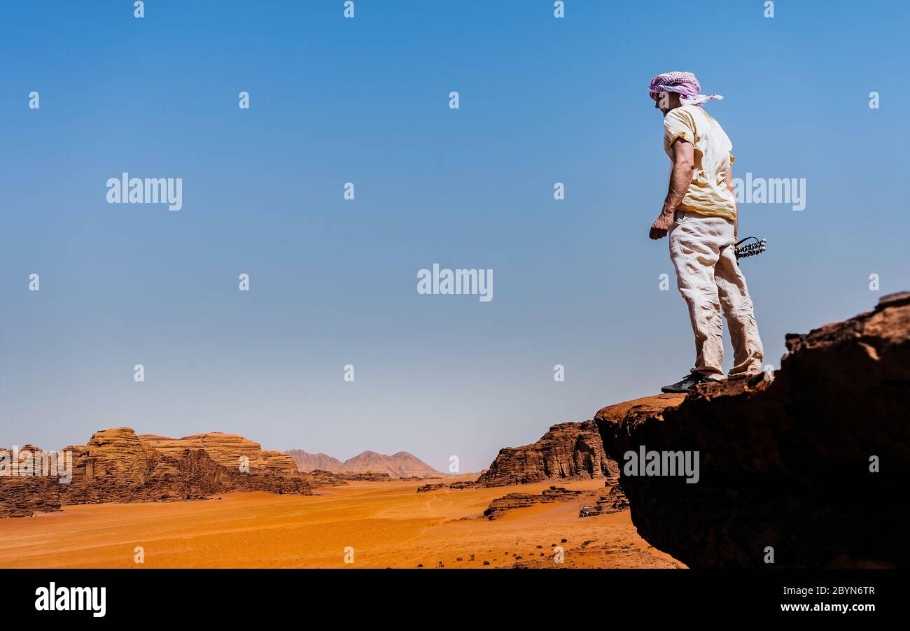 Le jeune homme est au sommet de la falaise. Wadi Rum, également connu sous le nom de la vallée de la Lune, est une vallée coupée dans la roche de grès et de granit dans le sud du Jourdain Banque D'Images