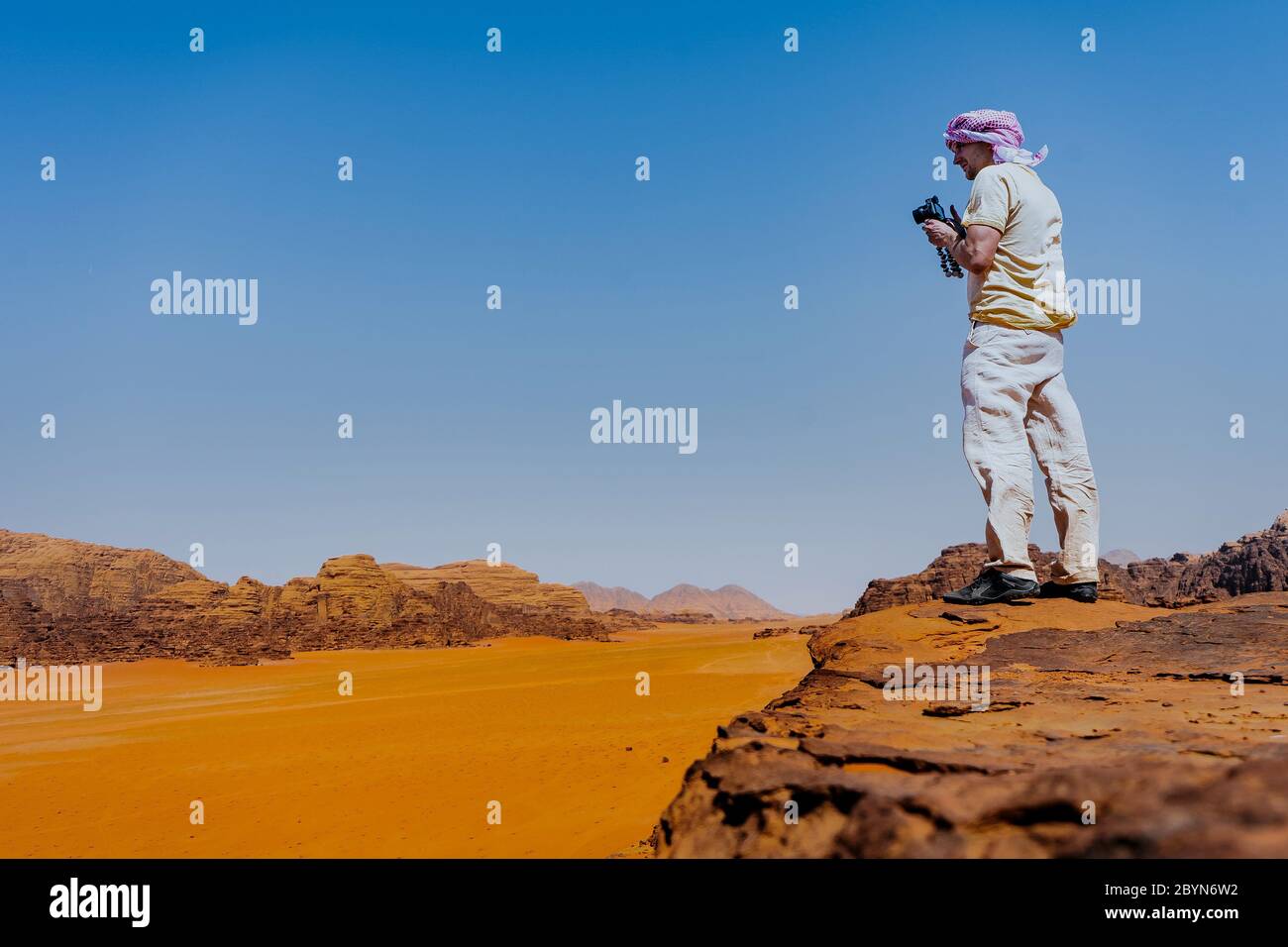 Le jeune homme est au sommet de la falaise. Wadi Rum, également connu sous le nom de la vallée de la Lune, est une vallée coupée dans la roche de grès et de granit dans le sud du Jourdain Banque D'Images