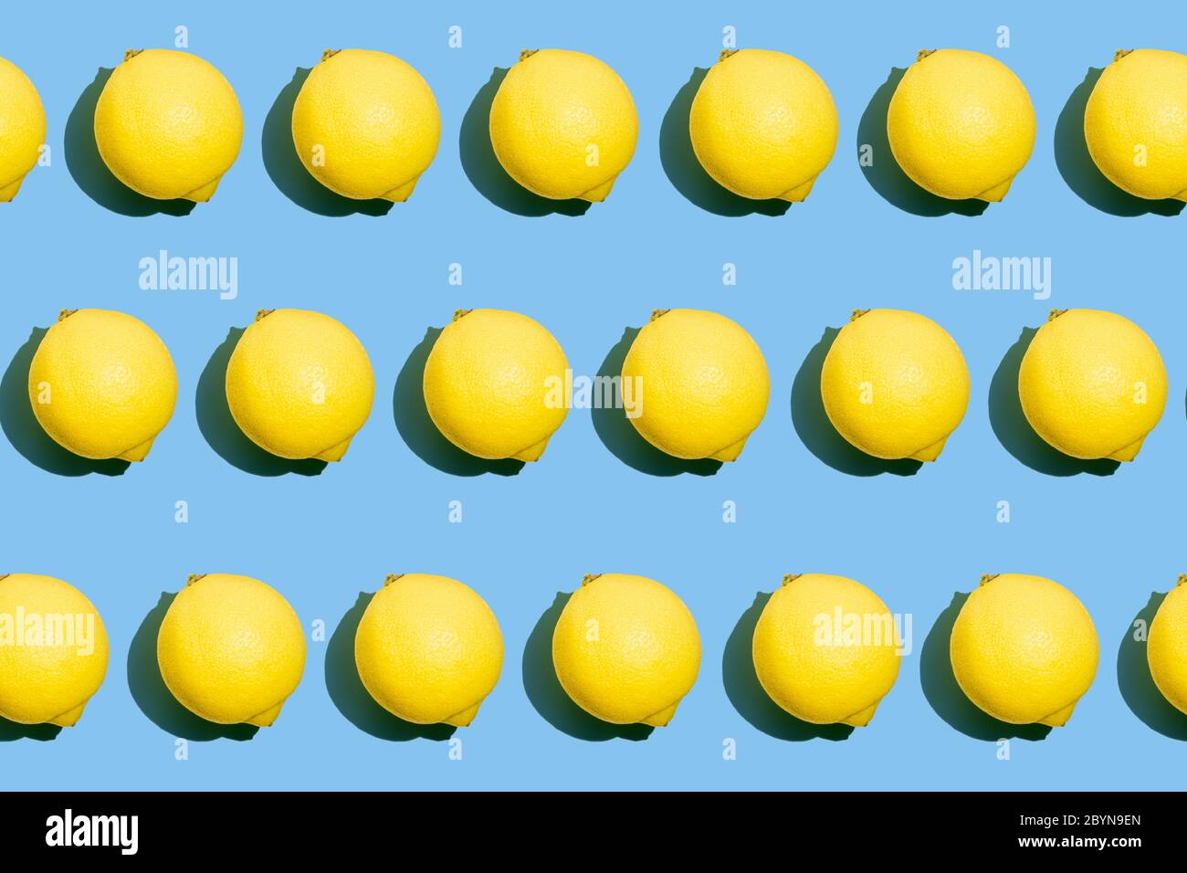 Répétition d'un motif photo sans couture de citrons jaunes entiers frais sur fond bleu. Texture des aliments. Banque D'Images