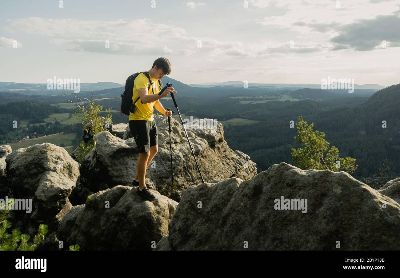 Grimpez sur le sentier de montagne avec des bâtons de randonnée et un sac à dos. Homme avec un équipement ultra-léger rester pour un moment sur la falaise Banque D'Images