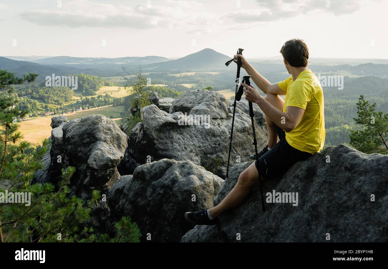 Grimpez sur le sentier de montagne avec des bâtons de randonnée et un sac à dos. Homme avec un équipement ultra-léger rester pour un moment sur la falaise Banque D'Images