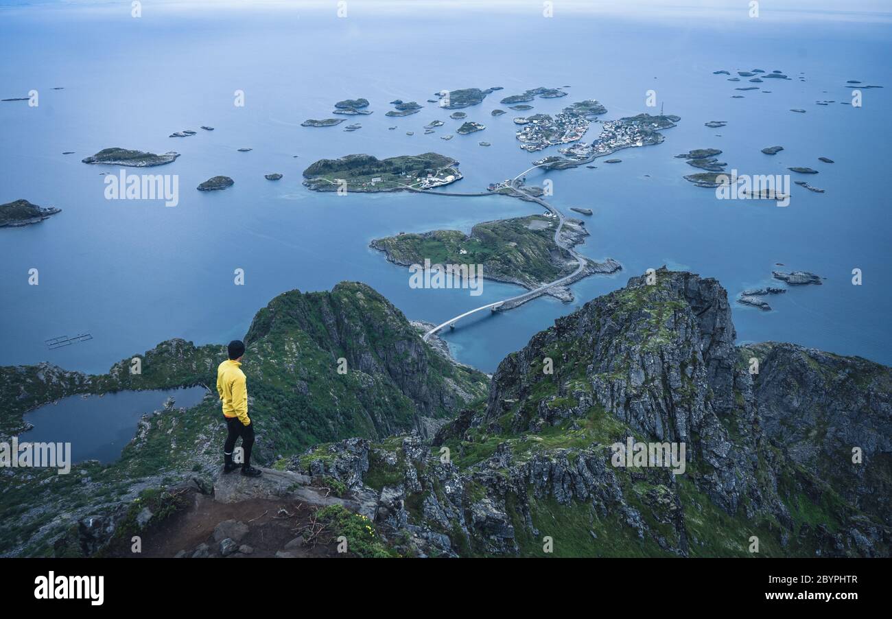Un randonneur haut avec vue panoramique sur la côte et les îlots de Henningsvaer. Vue sur la vallée depuis un point de vue vallonné Banque D'Images