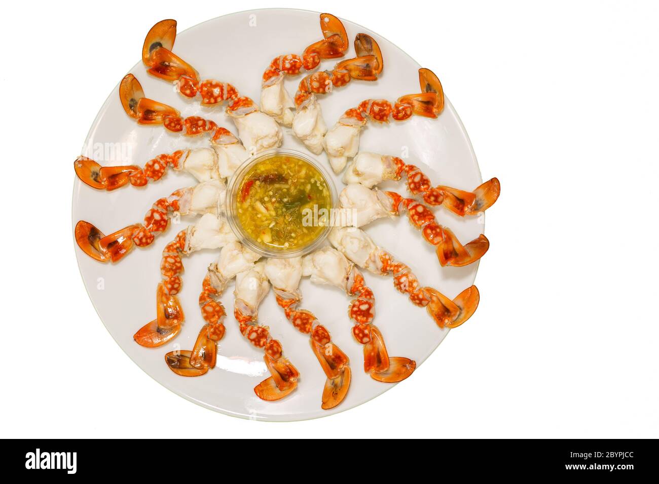 Crabe chaud frais sélectionnez une griffe de crabe sur une assiette avec sauce aux fruits de mer prête à servir sur fond blanc. Banque D'Images