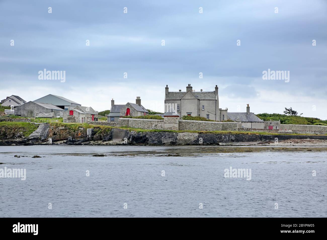 Côte avec galets et rochers et jetée de Sandsayre par une journée d'été grise, Sandwick, îles Shetland, Écosse. Banque D'Images