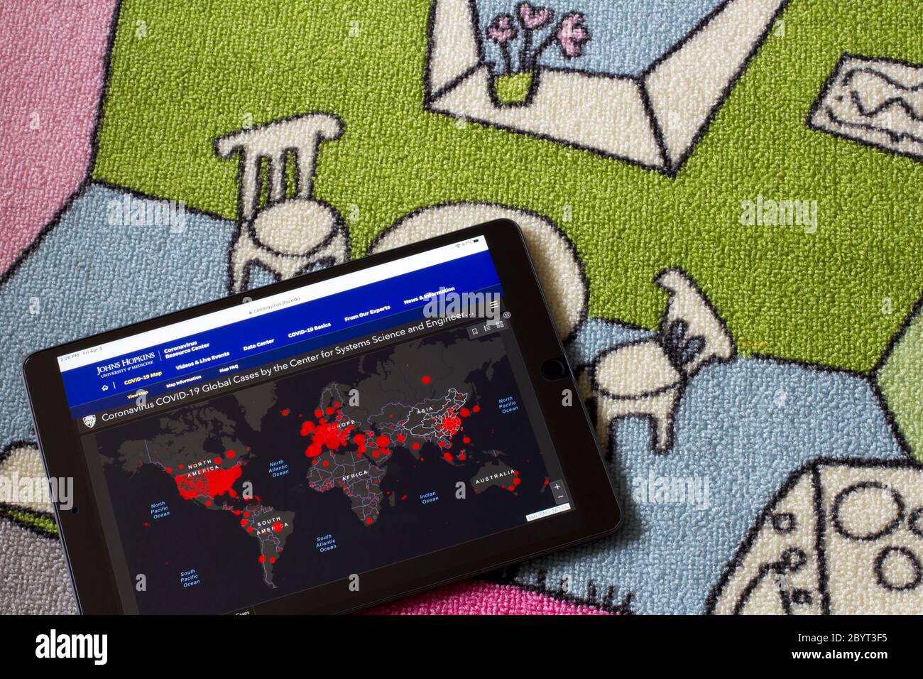 Un iPad sur le tapis de la chambre des enfants montrant une carte en direct des cas confirmés de COVID-19 dans le monde, créés par des chercheurs de CSSE à l'Université Johns Hopkins. Banque D'Images