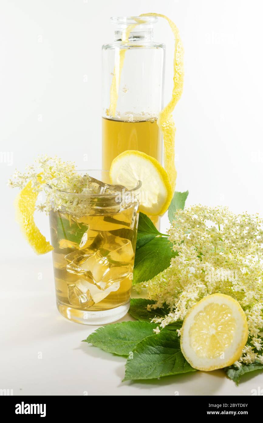 Sirop de fleurs de sureau dans une bouteille et limonade maison avec des glaçons, citron et quelques fleurs fraîches sur un fond blanc, espace de copie, Banque D'Images