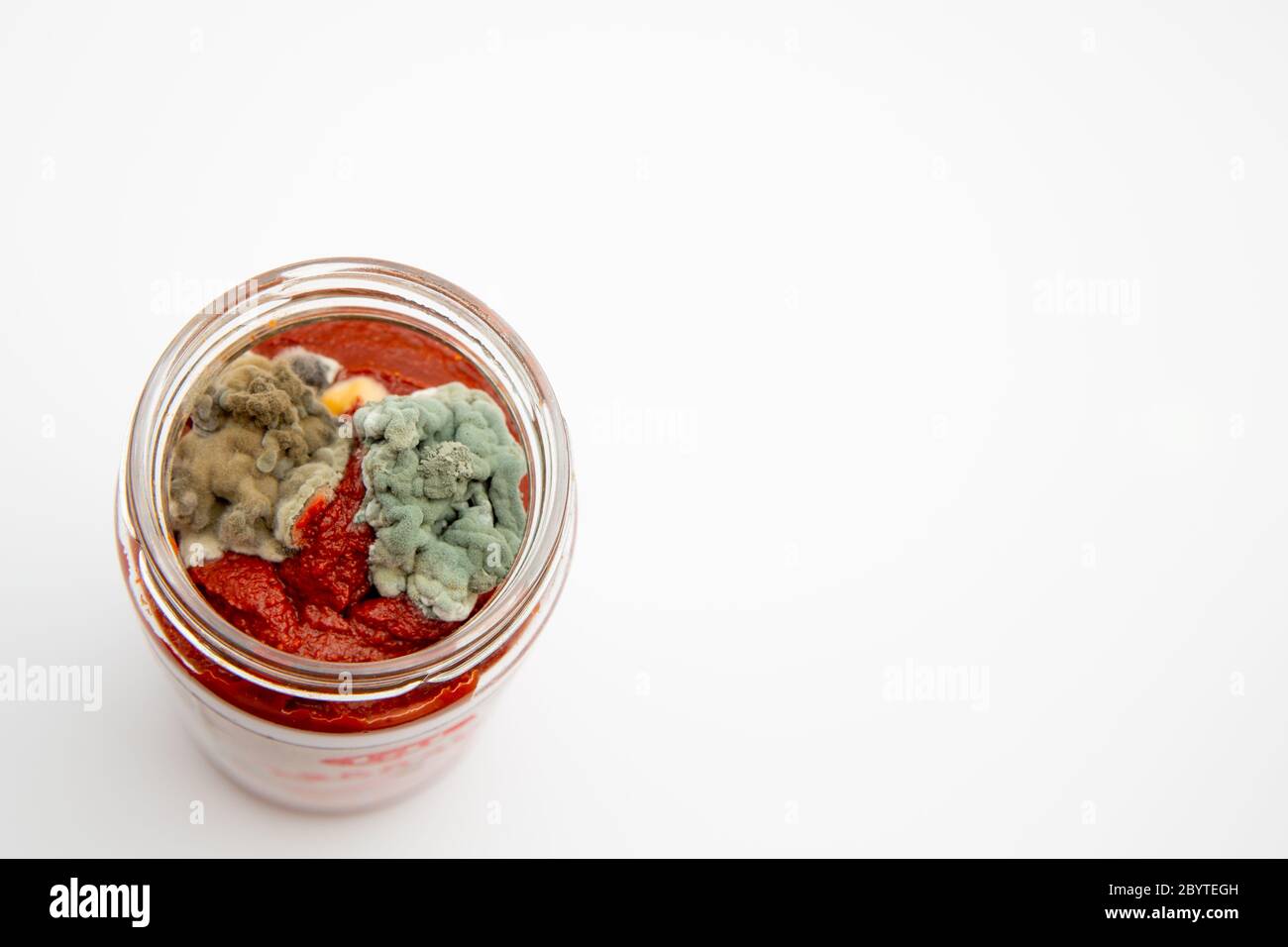 Gros plan de pâte de tomate moulysée dans un pot en verre isolé sur fond blanc avec espace de copie Banque D'Images